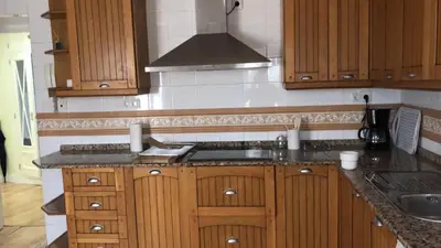 a kitchen with wooden cabinets and a stove at Cádiz San Pedro in Cádiz