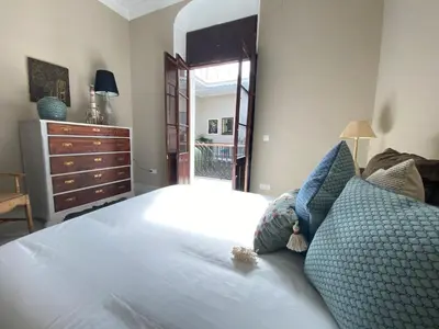 a bedroom with a bed with blue pillows and a dresser at Casa Palacio Ánima in Jerez de la Frontera
