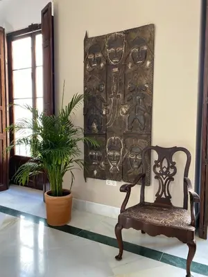 a chair and a plant in a room with a wall at Casa Palacio Ánima in Jerez de la Frontera