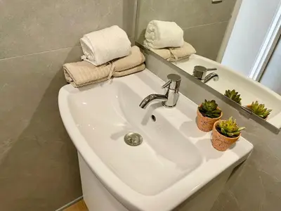 a white sink in a bathroom with towels and plants at GATU PREMIUM Villa Galeona, con terraza privada chillout in Cádiz