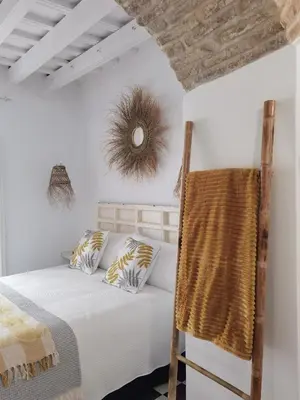 a bedroom with a bed and a rattan chair at Casa del Sacramento - CASITA CON ENCANTO in Medina Sidonia