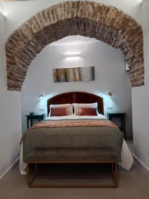 a bedroom with a large bed with a brick wall at Casa del Sacramento - CASITA CON ENCANTO in Medina Sidonia