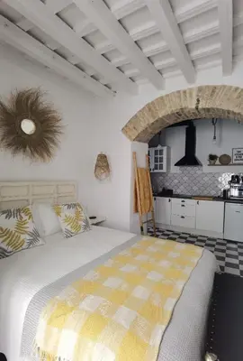 a white bedroom with a bed and a kitchen at Casa del Sacramento - CASITA CON ENCANTO in Medina Sidonia