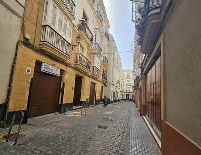 an empty alley with buildings and a person walking down the street at Casa Populi entre Catedral y Ayuntamiento in Cádiz