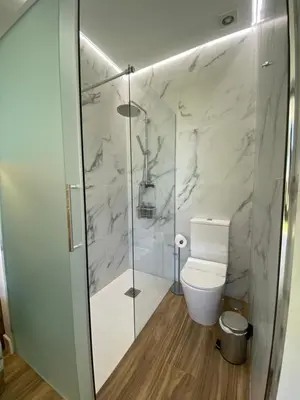 a bathroom with a toilet and a glass shower at VISTA LAGO VILLE in Chiclana de la Frontera