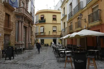 a person walking down a street with tables and chairs at Sweet Arco Rosa Zona Centro in Cádiz