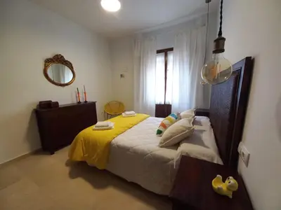 a bedroom with a bed with a yellow blanket and a mirror at LASPALOMAS18 in Sanlúcar de Barrameda