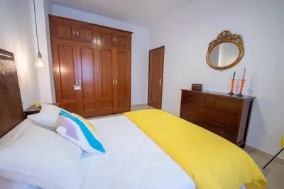 a bedroom with a bed with a yellow blanket on it at LASPALOMAS18 in Sanlúcar de Barrameda