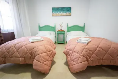two beds with ottomans in a bedroom at LASPALOMAS18 in Sanlúcar de Barrameda