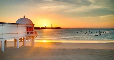 a lighthouse on the beach with birds in the water at La casa de la luz in San Fernando
