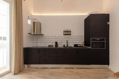 a kitchen with black cabinets and a black refrigerator at La Casa de Lima Little Apartments in Cádiz