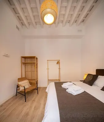 a bedroom with a large bed and a chair at La Casa de Lima Little Apartments in Cádiz