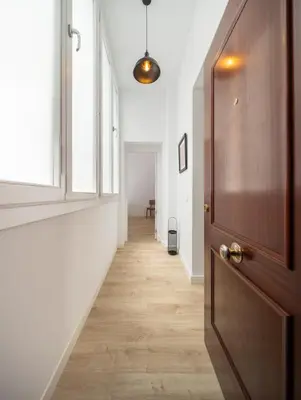 a hallway with a wooden door and a hallway with white walls at La Casa de Lima Little Apartments in Cádiz