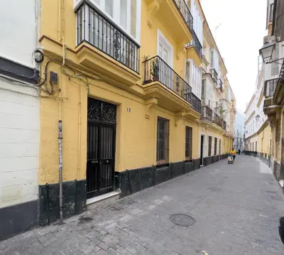 a yellow building on the side of a street at La Casa de Lima Little Apartments in Cádiz