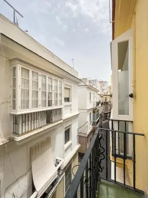 a balcony of a building with a chair on it at La Casa de Lima Little Apartments in Cádiz