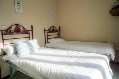 two beds with white sheets and a couch in a room at Atico BLUE Beach in El Puerto de Santa María