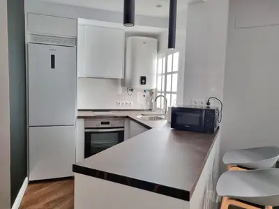 a kitchen with white appliances and a black counter top at Aujada playa in Cádiz