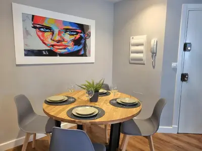 a dining room table with chairs and a painting on the wall at Aujada playa in Cádiz