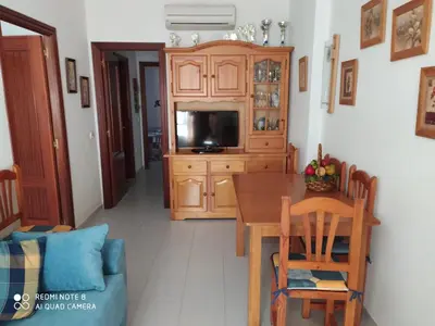 a kitchen with a wooden dining table and a tv at ALQUILER CHIPIONA in Chipiona