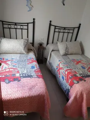a bedroom with two beds and a red car quilt at ALQUILER CHIPIONA in Chipiona