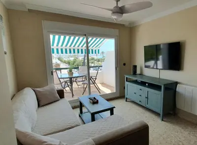 a living room with a couch and a flat screen tv at Apartamento a pie de playa La Barrosa in Chiclana de la Frontera