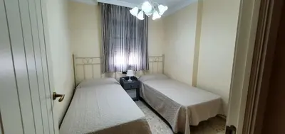a small room with two beds and a window at Apartamento a pie de playa La Barrosa in Chiclana de la Frontera