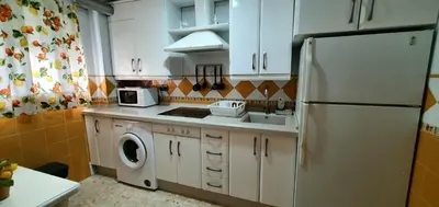 a kitchen with a white refrigerator and a washing machine at Apartamento a pie de playa La Barrosa in Chiclana de la Frontera