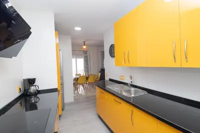 a kitchen with yellow cabinets and a sink at Piso San Roque in Sanlúcar de Barrameda