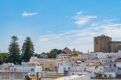 a group of white buildings with a castle in the background at Piso San Roque in Sanlúcar de Barrameda