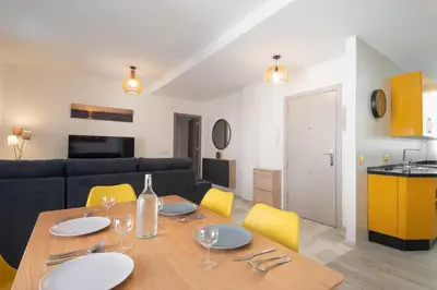 a dining room with a table and yellow chairs at Piso San Roque in Sanlúcar de Barrameda