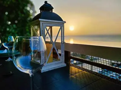 a wine glass and a lantern on a table with the ocean at Ático Reig frente al mar in Sanlúcar de Barrameda