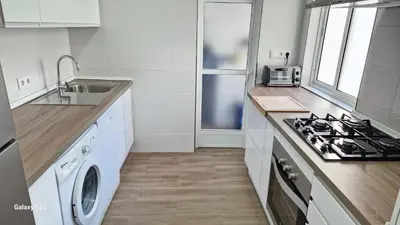 a kitchen with a stove top oven next to a sink at Ático Reig frente al mar in Sanlúcar de Barrameda
