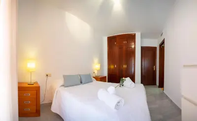 a bedroom with a white bed with towels on it at Brasil Playa Ha Apartment in Cádiz