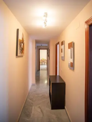 a hallway of a house with a table and paintings on the walls at Brasil Playa Ha Apartment in Cádiz