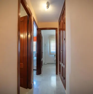 a hallway with wooden doors and a room with a window at Brasil Playa Ha Apartment in Cádiz