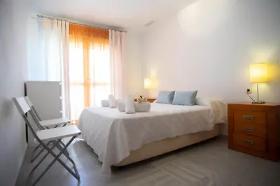 a bedroom with a bed with a chair and a window at Brasil Playa Ha Apartment in Cádiz