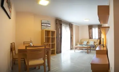 a dining room and living room with a table and chairs at Brasil Playa Ha Apartment in Cádiz