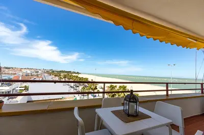 a table and chairs on a balcony with a view of the beach at Mirador del Guadalquivir in Sanlúcar de Barrameda