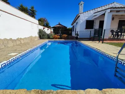 a large blue swimming pool next to a house at El Cortijo de Pepa in Conil de la Frontera