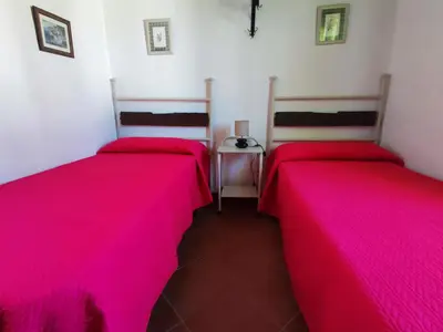 two beds in a room with pink sheets at El Cortijo de Pepa in Conil de la Frontera