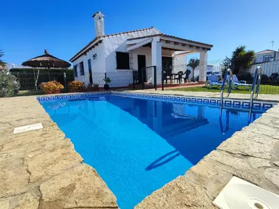 a swimming pool in front of a house at El Cortijo de Pepa in Conil de la Frontera
