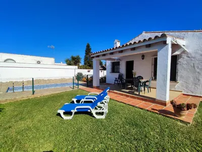 a yard with two lounge chairs and a house at El Cortijo de Pepa in Conil de la Frontera