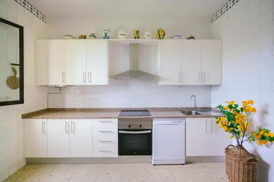 a kitchen with white cabinets and a sink and a stove at Villa La Jara Sanlúcar in Sanlúcar de Barrameda