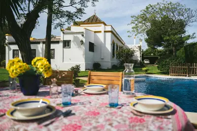 a table with a table cloth with plates and glasses at Villa La Jara Sanlúcar in Sanlúcar de Barrameda