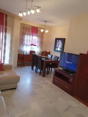 a living room with a television and a table with chairs at Luceros in Rota