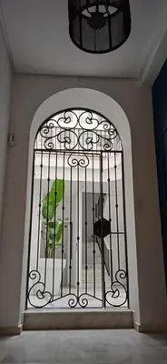 an iron gate with a green bird sitting inside at el 2 de Flamenco 1ºB in Cádiz