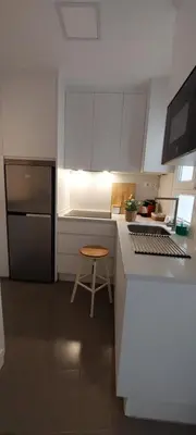 a kitchen with white cabinets and a stool in it at el 2 de Flamenco 1ºA in Cádiz