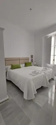 a white bedroom with two beds and a window at el 2 de Flamenco 2ºA in Cádiz