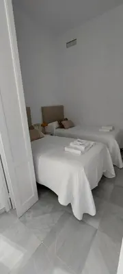 a white room with two beds and a table at el 2 de Flamenco 2ºA in Cádiz
