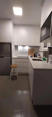 a kitchen with white cabinets and a stool in it at el 2 de Flamenco 2ºA in Cádiz